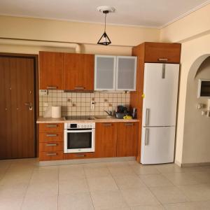 a kitchen with wooden cabinets and a white refrigerator at vaccation appartement in Káto Almirí