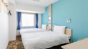 2 łóżka w pokoju z niebieskimi ścianami w obiekcie Toyoko Inn Kasukabe-eki Nishi-guchi w mieście Kasukabe