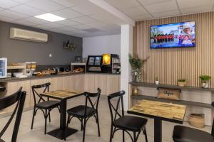 a restaurant with a table and chairs and a counter at The Originals City, Hôtel Azur, Fos-sur-Mer in Fos-sur-Mer