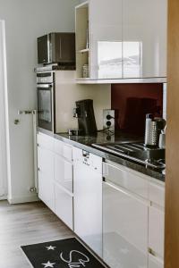 a kitchen with white cabinets and black counter tops at Ferienwohnung Waldfeeling in Brilon