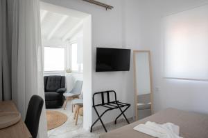 a white room with a bed and a tv on a wall at Aegean Eyes 3bd House Βy the Sea in Kefalos