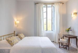 Un dormitorio con una gran cama blanca y una ventana en Logis Hôtel Restaurant Château Bellevue, en Cazaubon