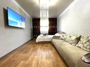 ein Wohnzimmer mit einem Sofa und einem Flachbild-TV in der Unterkunft Абая 68 квартира в центре, 4 спальных места in Petropawlowsk