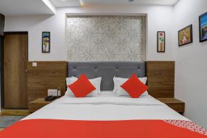 a bedroom with a large bed with red pillows at OYO Hotel R S Palace in Ahmedabad