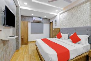 a bedroom with a bed with red pillows and a tv at OYO Hotel R S Palace in Ahmedabad