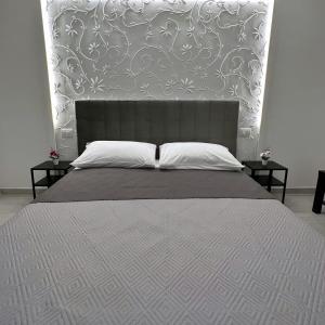 a bed with a large headboard and two tables at Cuore D'aMare B&B in Bari