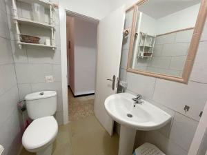 a white bathroom with a toilet and a sink at Edificio Playa in Los Cristianos