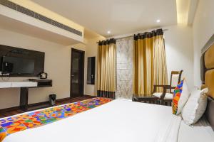um quarto com uma cama grande e uma televisão em FabHotel Grand Stay em Nova Deli
