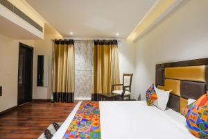 een slaapkamer met een groot bed en een stoel bij FabHotel Grand Stay in New Delhi