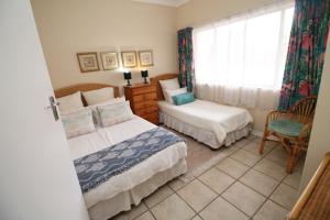 a bedroom with two beds and a window and a chair at Nellelani No 6 in Margate