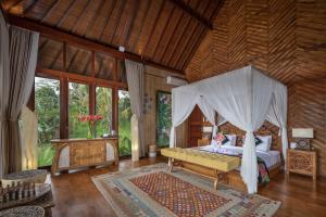 ein Schlafzimmer mit einem Himmelbett in einem Zimmer in der Unterkunft Villa Lembah Damai by Pramana Villas in Gianyar