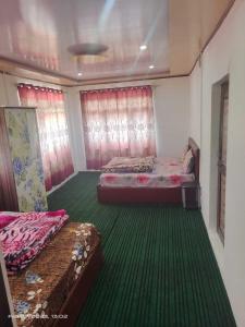 1 dormitorio con 2 camas y alfombra verde en OYO Home Homestay Sabzar Ahmad Gorsi, en Pahalgām