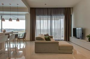 a living room with a couch and a table with a television at Land's End, Boutique Hotel in Sliema