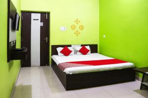 a bedroom with a bed with green walls and red pillows at OYO 86877 Hotel Bhuneshwar Inn in Rāmgarh