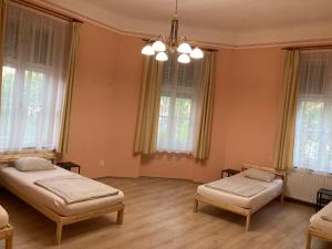 two beds in a room with windows and a chandelier at Gogol24 in Szeged +9 photos