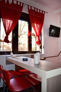 a room with red curtains and a desk with red chairs at Apartmants Night Lux in Niš