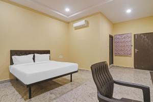a bedroom with a bed and a chair at Super Capital O Hotel Sai Balaji Near Golconda Fort in Hyderabad