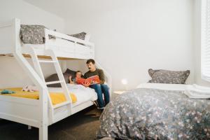 a man and a child sitting on a bunk bed at 4 - Charming Space, Just a Stone Throw from Central Wanaka in Wanaka