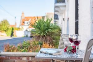 una mesa con dos copas de vino y un libro en Eden Cottage en Wells next the Sea