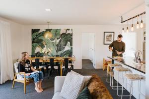un uomo in piedi in un soggiorno accanto a un tavolo di 4 - Charming Space, Just a Stone Throw from Central Wanaka a Wanaka