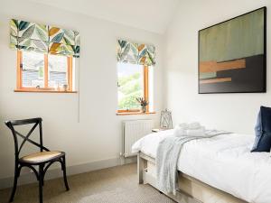 a bedroom with a bed and a chair and two windows at Lantern Lodge in Bramley