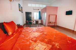 a large orange bed in a room with a living room at Lea's Guesthouse and Restaurant in Phumĭ Phlov Phnum Pénh