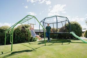 un hombre parado en un patio de juegos con dos columpios en 4 - Charming Space, Just a Stone Throw from Central Wanaka, en Wanaka