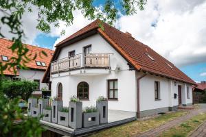 a white house with a balcony at Ackerweg Ferienwohnungen in Ueckeritz