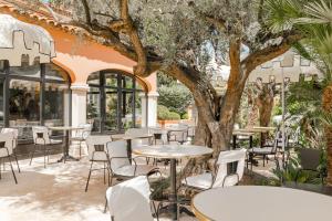 d'une terrasse avec des tables, des chaises et un arbre. dans l'établissement La Bastide de Saint Tropez, à Saint-Tropez
