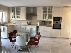een keuken met witte kasten en een glazen tafel en stoelen bij Villa CHELSEA in Vilamoura