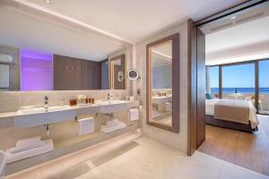 a bathroom with two sinks and a bedroom with a bed at Amathus Beach Hotel Limassol in Limassol