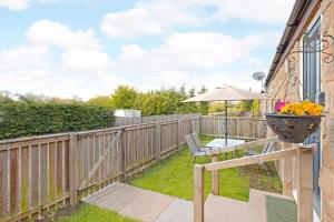 une terrasse avec une table et un parasol sur une clôture dans l'établissement Plum Cottage, à Knaresborough