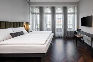 a bedroom with a large white bed and a desk at AMANO Home Leipzig in Leipzig