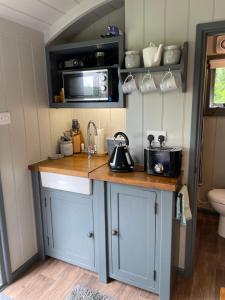 a kitchen with a counter with a sink and a microwave at Greatwood Shepherds Hut in Battle