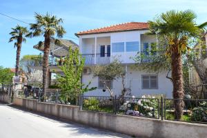 a white house with palm trees and a fence at Apartment Vlado in Sukošan