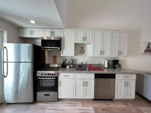 a kitchen with white cabinets and a stainless steel refrigerator at Hollywood Loft Modern Style 1 Bedroom in Los Angeles