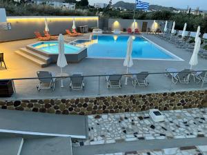 a large swimming pool with chairs and umbrellas at Family House Faliraki Studios Apartments in Faliraki