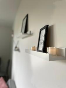 a shelf with a clock and candles on a wall at Modern Suite- Bedford City centre with free gym & parking in Bedford