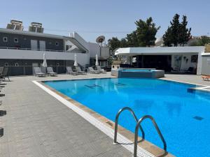 duży niebieski basen obok budynku w obiekcie Family House Faliraki Studios Apartments w mieście Faliraki