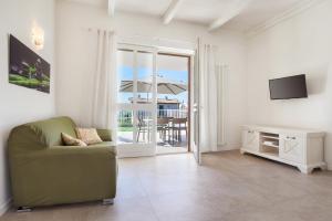 ein Wohnzimmer mit einem Sofa, einem TV und einem Balkon in der Unterkunft Villa Chiara APT 1- Appartamento in villa con piscina in Cavaion Veronese
