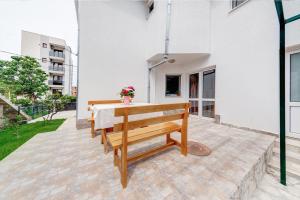 eine Holzbank auf einer Terrasse mit einem Tisch in der Unterkunft Holiday Home Adria in Dobra Voda