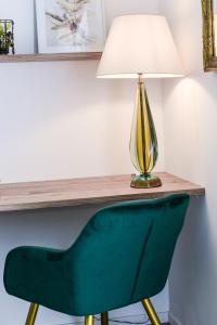 Una silla verde debajo de una mesa con una lámpara. en Residenza Emilia, en Padua