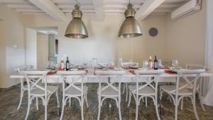 uma grande mesa branca com cadeiras e garrafas de vinho em Casale San Vincenti em Gaiole in Chianti