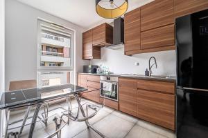 a kitchen with wooden cabinets and a glass table at Kolska Grey Apartment in Warsaw