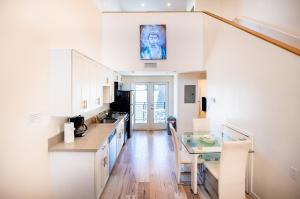 a kitchen with white cabinets and a glass table at Hollywood Sign View in Modern 1 Bedroom Loft in Los Angeles