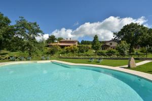 una gran piscina con sillas y una casa en el fondo en Melograno en Roccalbegna