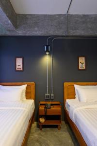 a bedroom with two beds and a nightstand between them at Na BaanYa Chiang Mai in Chiang Mai