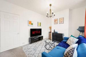 ein Wohnzimmer mit einem blauen Sofa und einem TV in der Unterkunft Aesthetic Cambridge Cottage sleeps 5! in Cambridge
