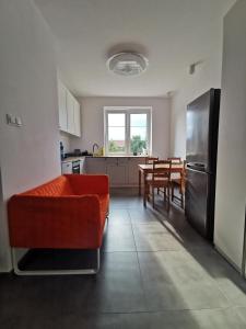 a living room with a red couch and a kitchen at Comfortable apartment close to the center and sea in Gdańsk