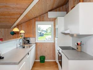 a kitchen with white cabinets and a window at 6 person holiday home in Hj rring in Lønstrup